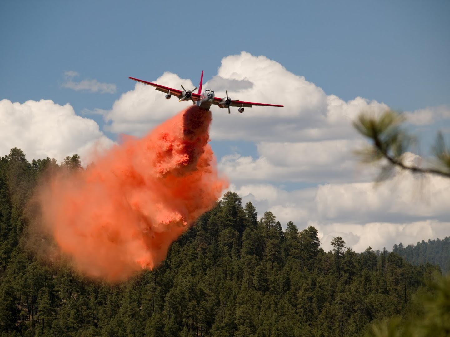 A fixed wing aircraft dropping fire retardant