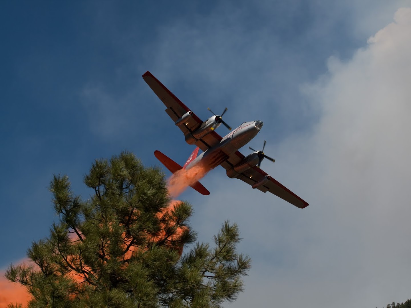 A fixed wing aircraft dropping fire retardant